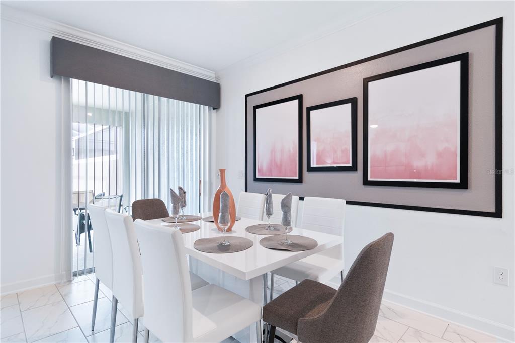 A dining room features a white table, six chairs, and three framed abstract art pieces — 1060 LEADER STREET, DAVENPORT, FL