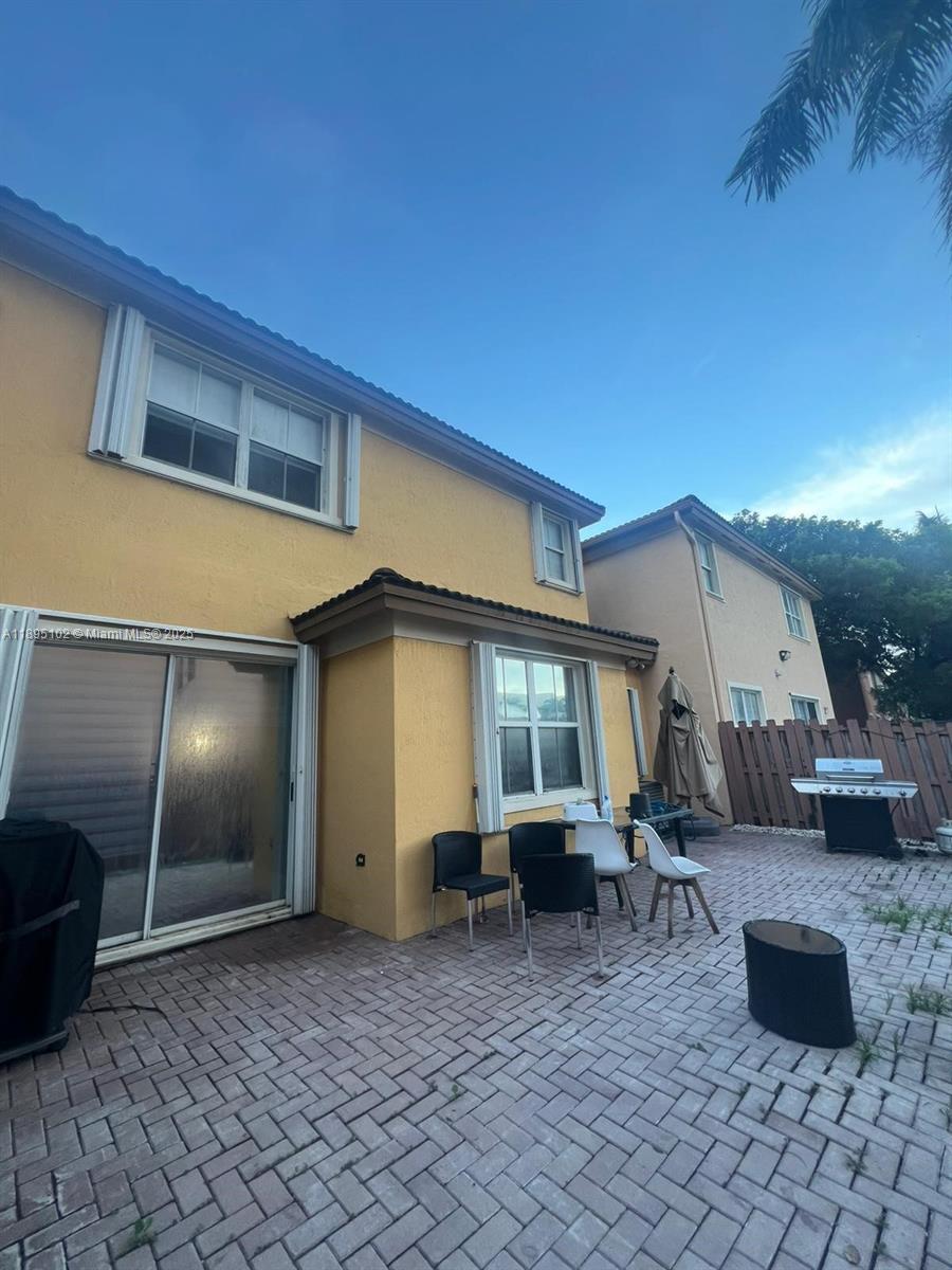 A backyard patio features a paved brick floor, outdoor furniture, and a grill — 11281 NW 84th St, Doral FL 33178, DORAL, FL