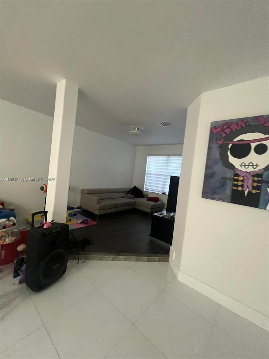 A living room features dark wood flooring, a light-colored sectional sofa, and white tile flooring — 11281 NW 84th St, Doral FL 33178, DORAL, FL