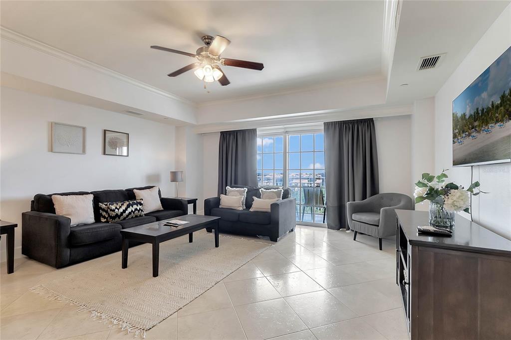 A living room features dark sofas, a coffee table, tile flooring, and a sliding glass door — 7593 GATHERING DRIVE UNIT 504, KISSIMMEE, FL