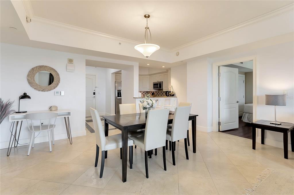 A dining area with a dark table and white chairs sits near a kitchen — 7593 GATHERING DRIVE UNIT 504, KISSIMMEE, FL