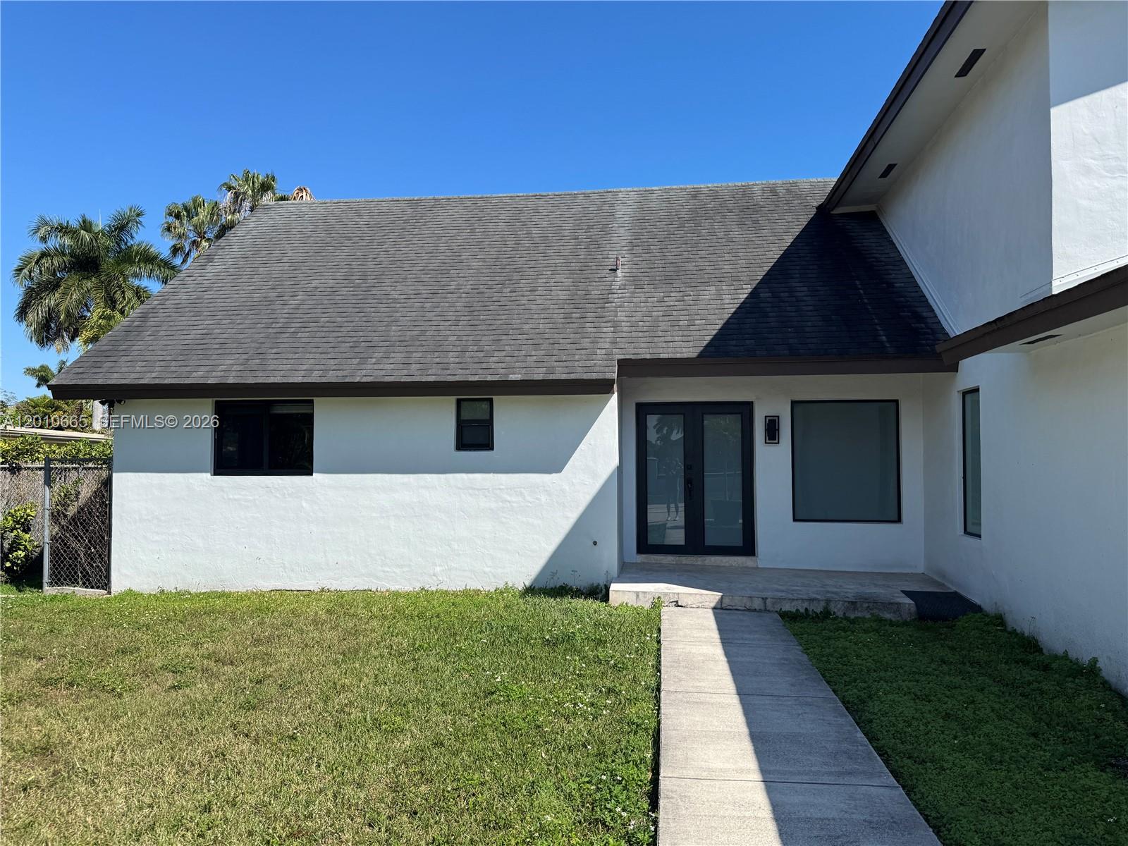 A white house exterior features a dark shingled roof, black-framed windows, and a double door — 3155 SW 132nd Ave, Miami FL 33175, MIAMI, FL
