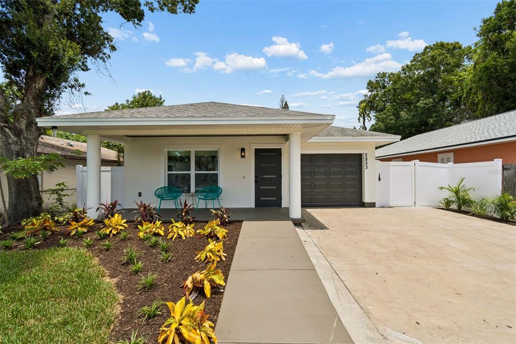 A single-story house with a white exterior, a covered porch, and a dark garage door — 2853 35TH AVENUE N, ST PETERSBURG, FL
