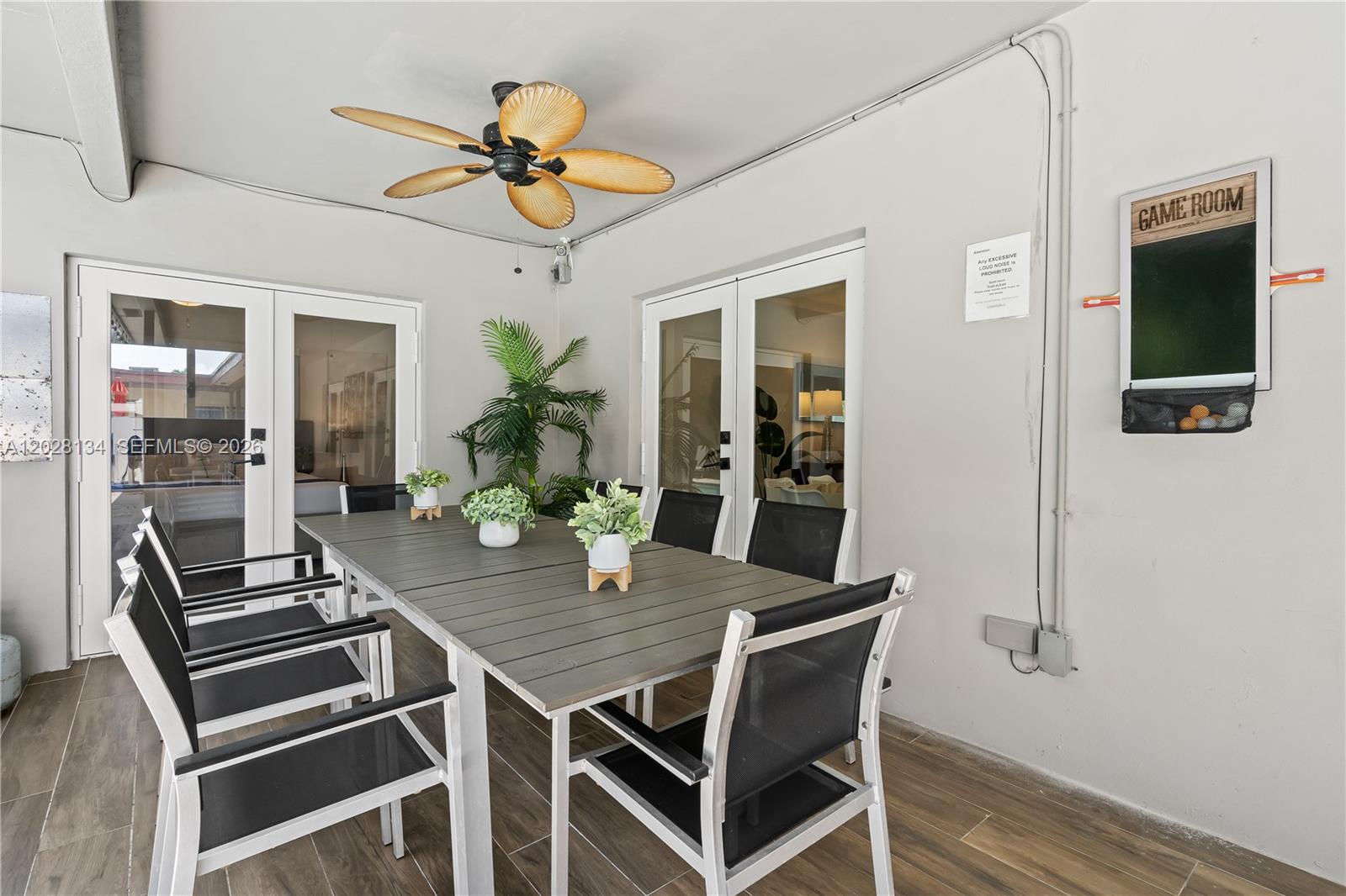 A covered outdoor patio features a dining table, chairs, a ceiling fan, and a game board — 1329 Funston, Hollywood FL 33019, HOLLYWOOD, FL