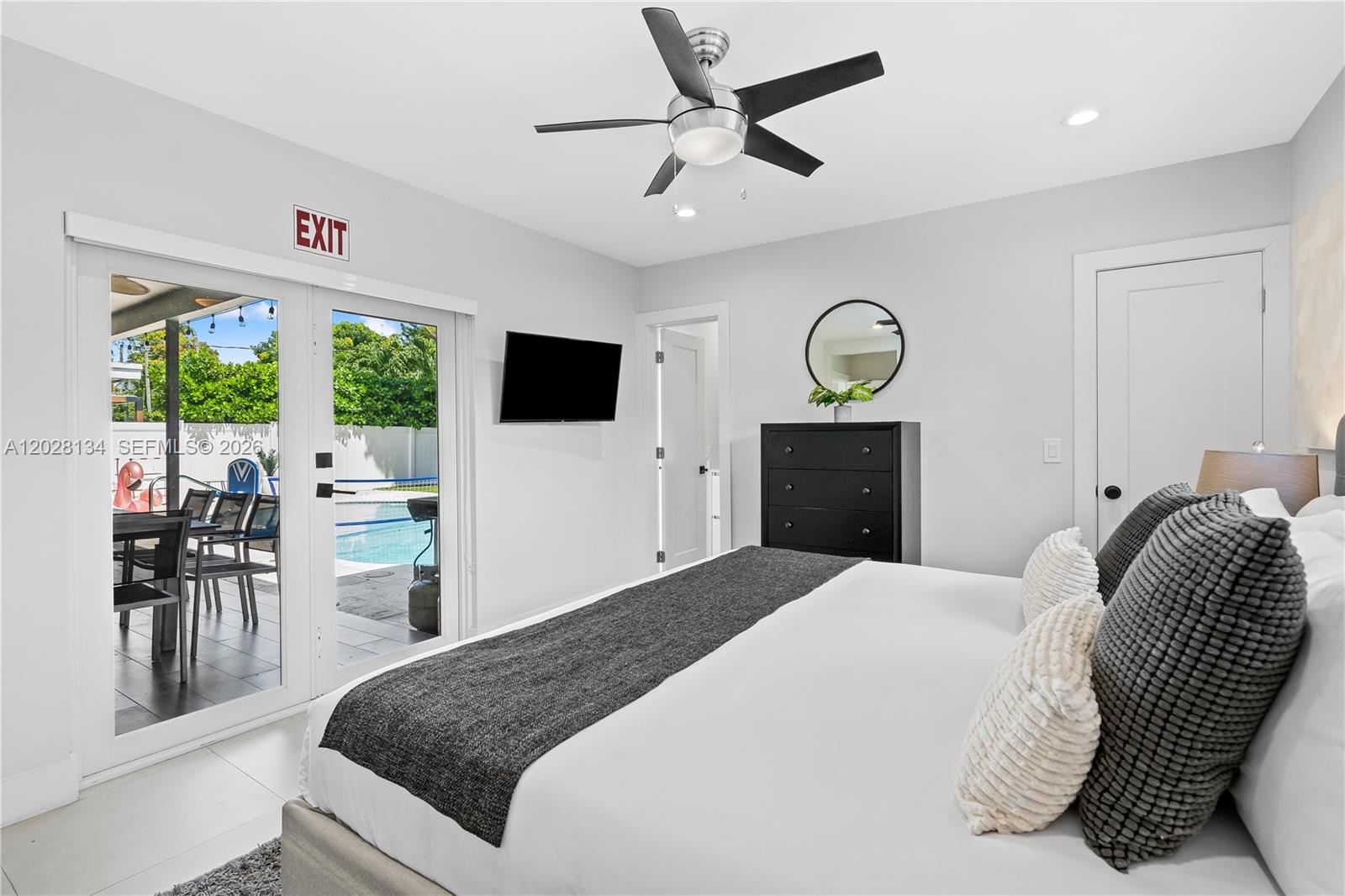 A bedroom features a king bed, ceiling fan, black dresser, and glass doors to a pool — 1329 Funston, Hollywood FL 33019, HOLLYWOOD, FL