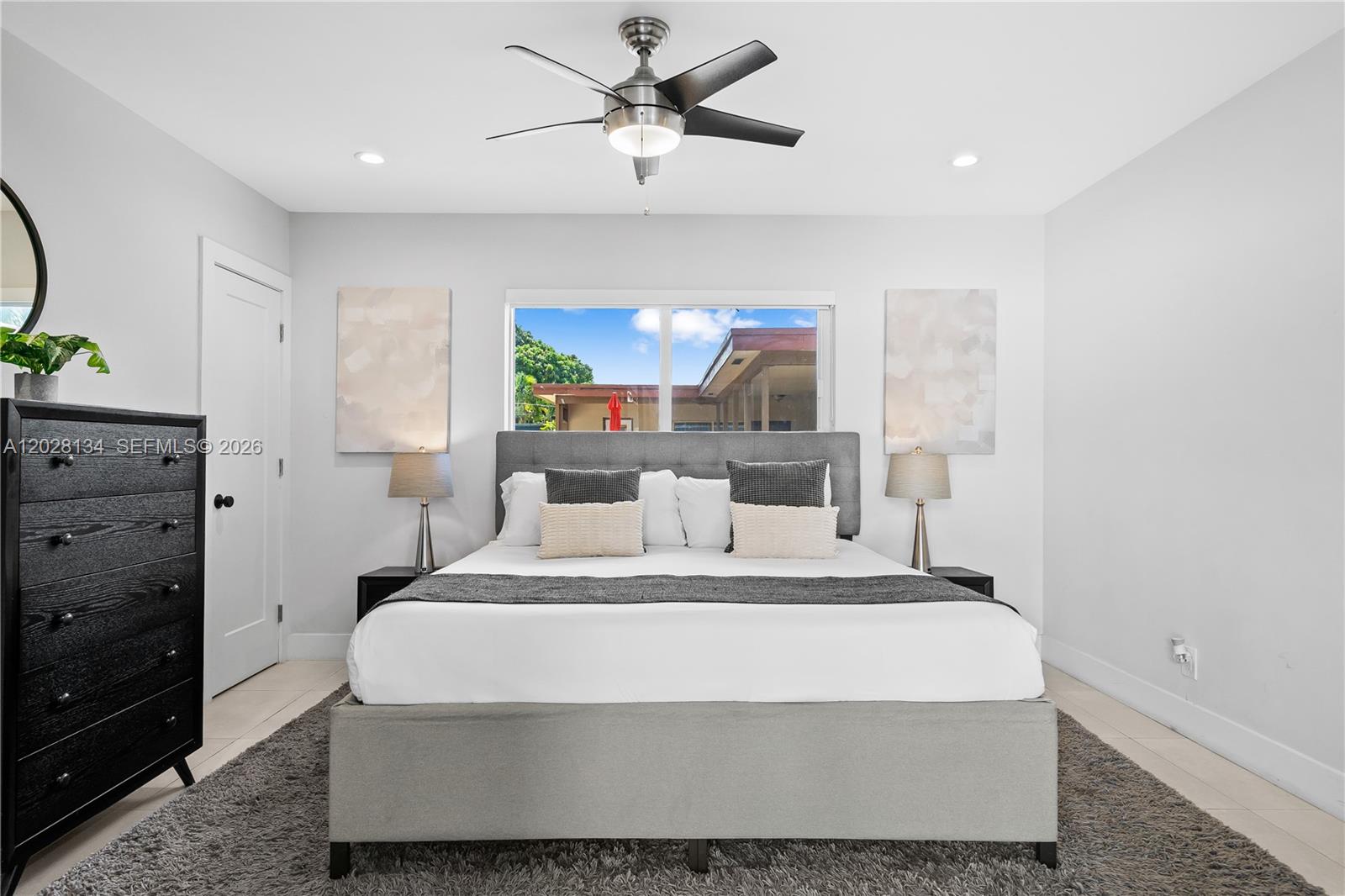 A bedroom features a gray upholstered bed, black dresser, and a ceiling fan — 1329 Funston, Hollywood FL 33019, HOLLYWOOD, FL