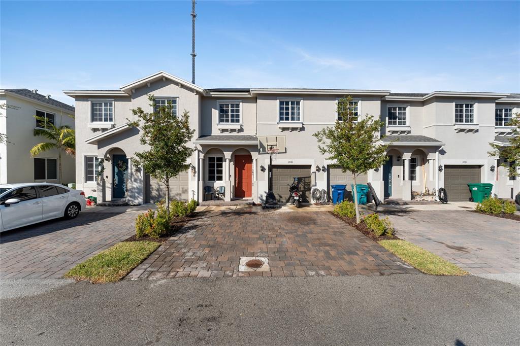 A row of two-story townhouses with paved driveways, garage doors, and small front trees — 1061 NW 208TH TERRACE, MIAMI, FL