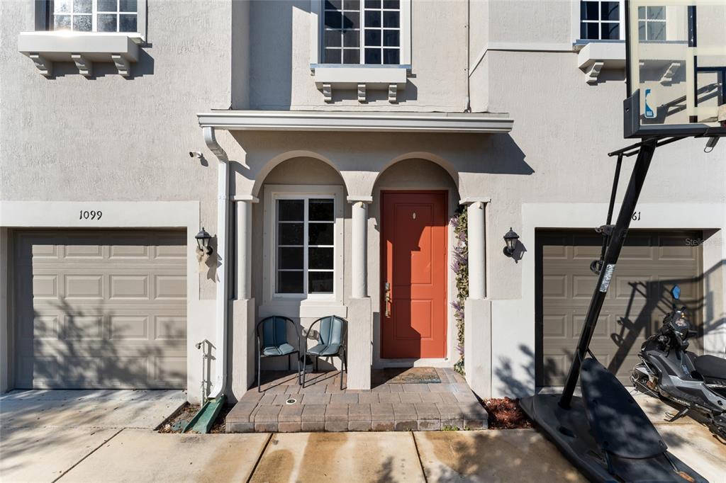 The exterior of a townhouse features a red front door, two garage doors, and a basketball hoop — 1061 NW 208TH TERRACE, MIAMI, FL