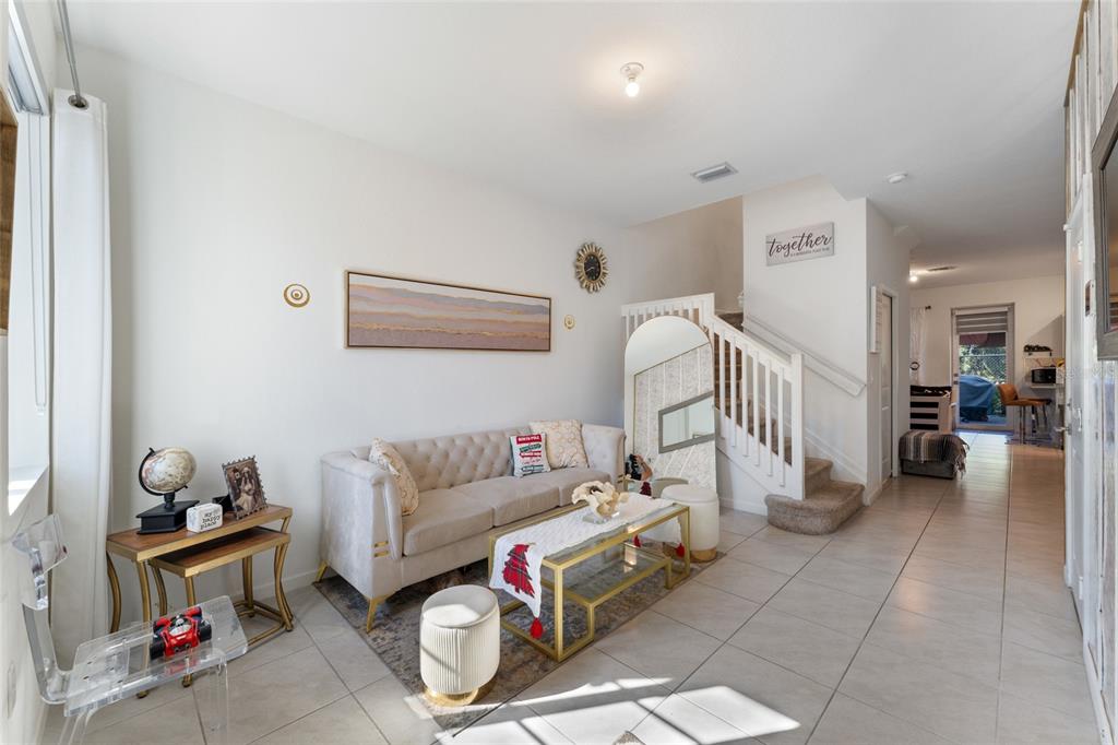 A living room features a tufted sofa, a glass coffee table, and a staircase — 1061 NW 208TH TERRACE, MIAMI, FL