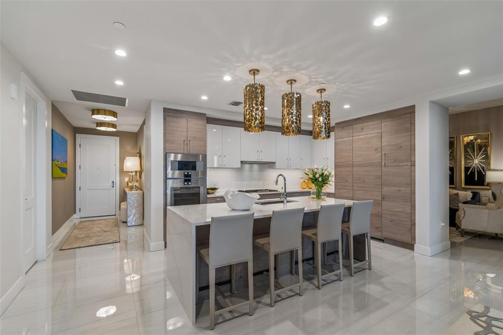 A modern kitchen features a white island with four chairs, wood cabinetry, and pendant lighting — 2103 BAYSHORE BOULEVARD UNIT 1203, TAMPA, FL