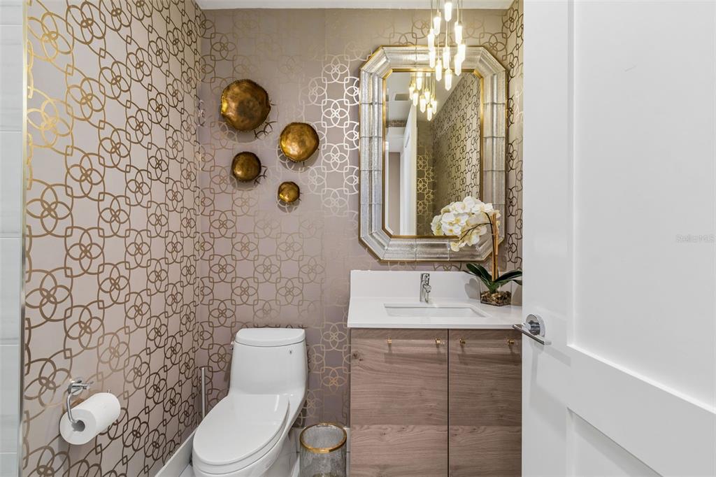 A powder room features patterned wallpaper, a wood vanity, a white toilet, and a decorative mirror — 2103 BAYSHORE BOULEVARD UNIT 1203, TAMPA, FL