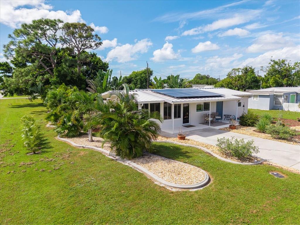 An exterior view of a white house with solar panels and a landscaped front yard — 2830 10TH STREET, ENGLEWOOD, FL