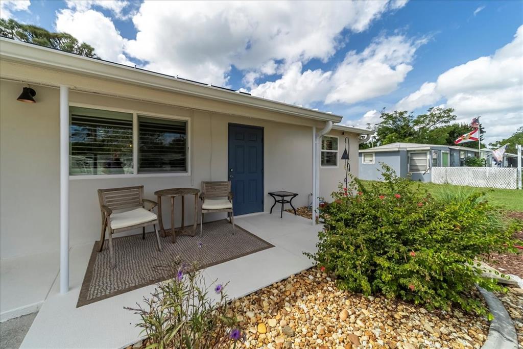A small patio with two chairs and a table sits in front of a blue door — 2830 10TH STREET, ENGLEWOOD, FL