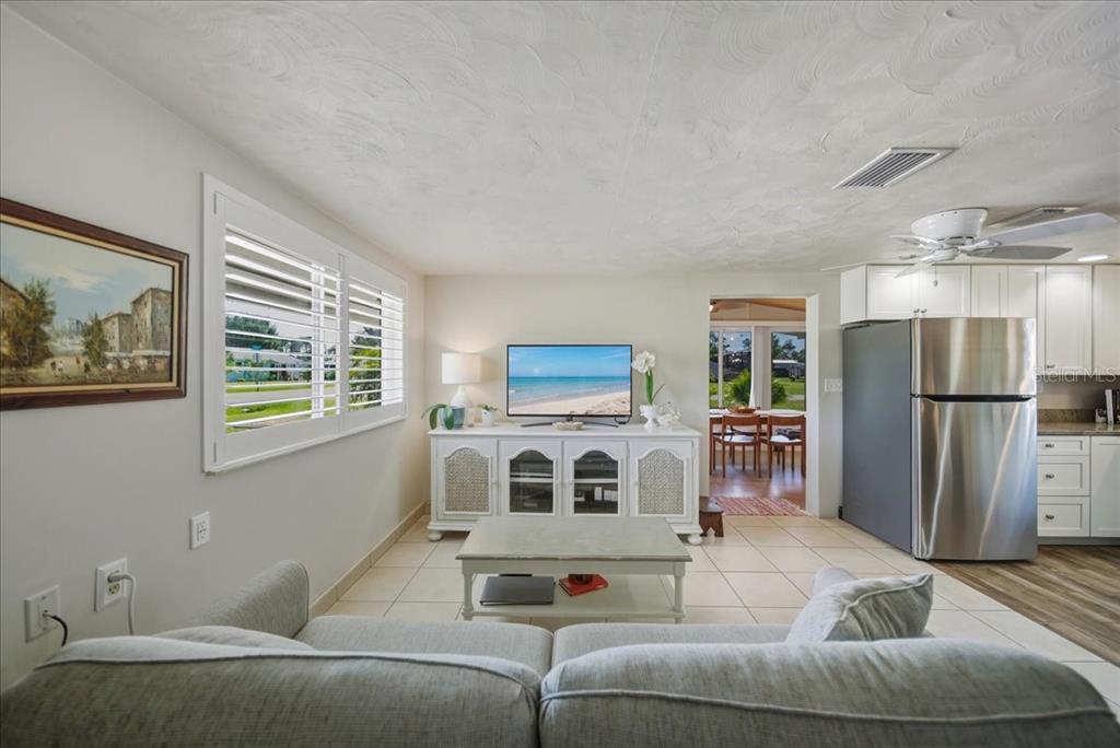 A living room with a gray sofa, white media console, and an adjacent kitchen area — 2830 10TH STREET, ENGLEWOOD, FL