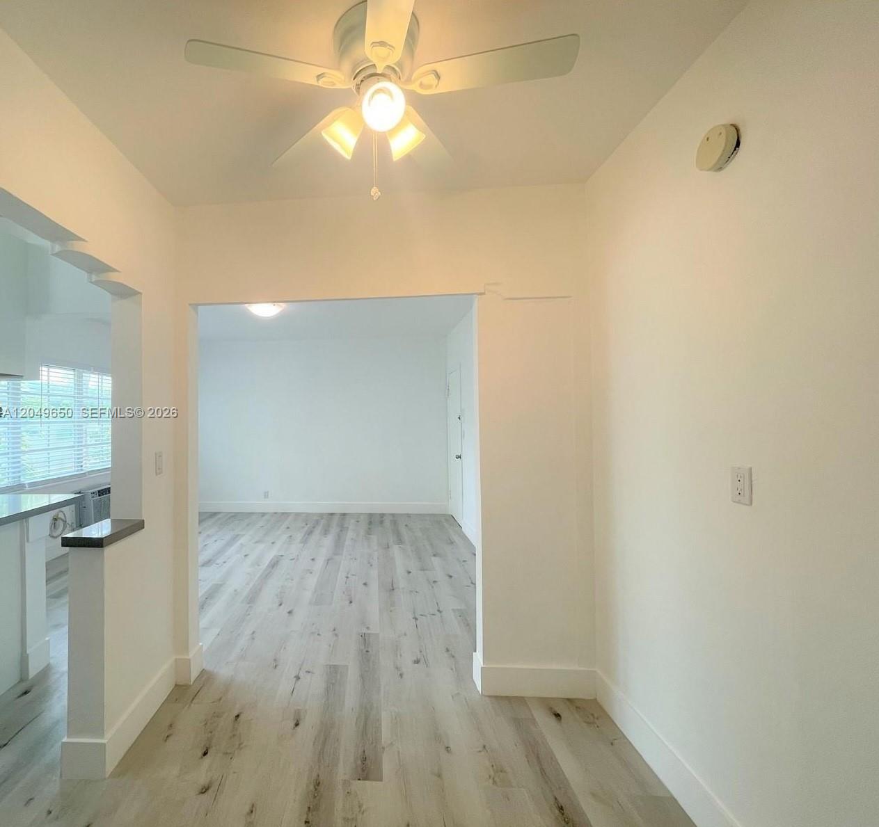 A view through a doorway into a room with light-colored wood-look flooring and ceiling fans — 1021 Euclid Ave # 9, Miami Beach FL 33139, MIAMI BEACH, FL