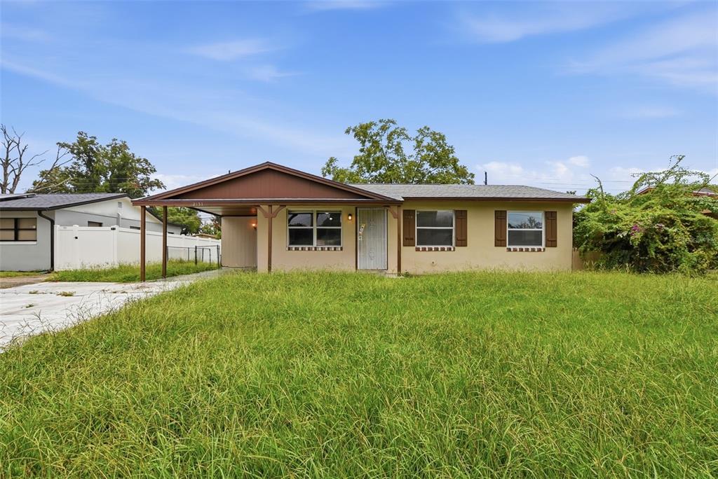 A single-story house with a brown roof, a carport, and an overgrown front lawn — 2151 S IVEY LANE, ORLANDO, FL
