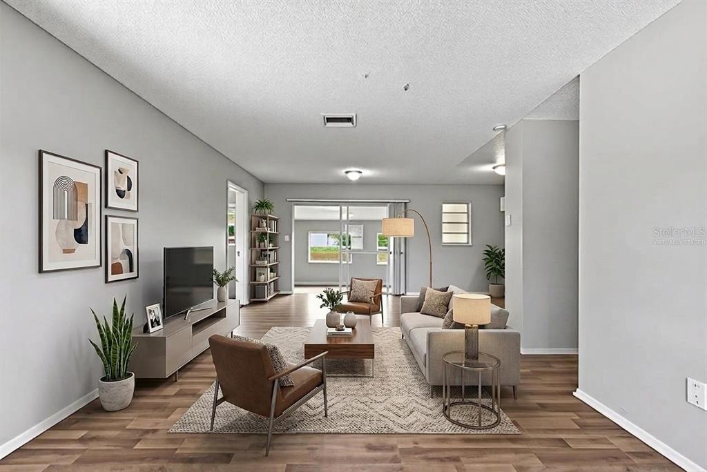 This is a virtually staged living room featuring wood-look flooring, a gray sofa, and neutral walls — 2151 S IVEY LANE, ORLANDO, FL