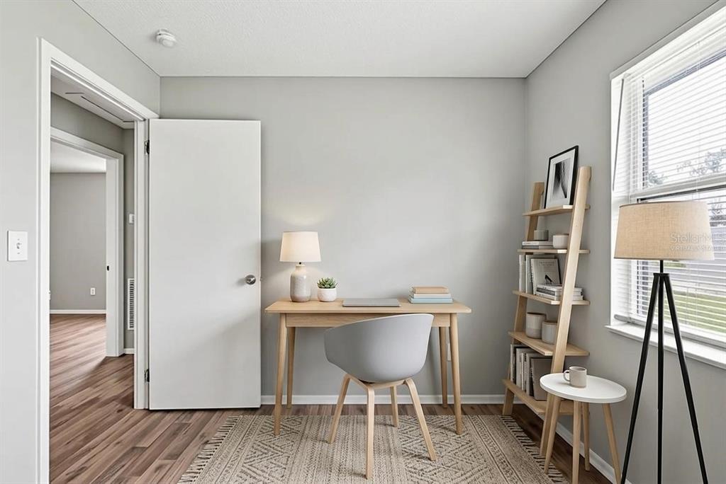 A home office with a wooden desk, gray chair, ladder shelf, and a floor lamp — 2151 S IVEY LANE, ORLANDO, FL