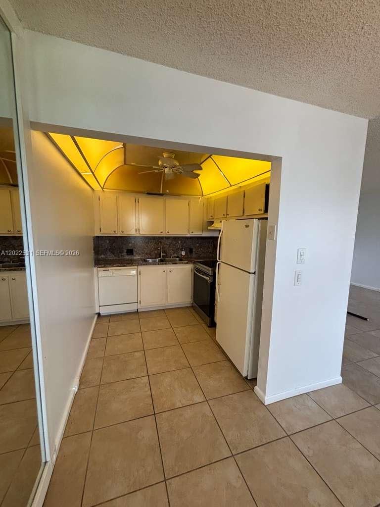 A galley kitchen features white cabinets, white appliances, and a yellow-lit soffit ceiling — 531 Fanshaw M # 531, Boca Raton FL 33434, BOCA RATON, FL