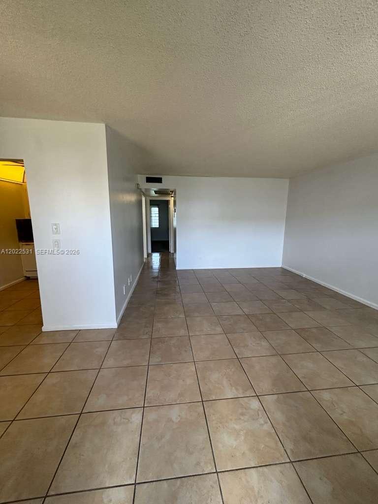An empty room features light-colored tile flooring and a hallway leading to another area — 531 Fanshaw M # 531, Boca Raton FL 33434, BOCA RATON, FL