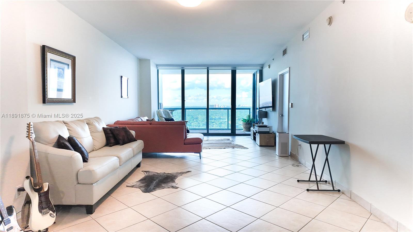 A living room features a white sofa, a reddish-brown sectional, and floor-to-ceiling windows — 601 NE 36th St # 2206, Miami FL 33137, MIAMI, FL