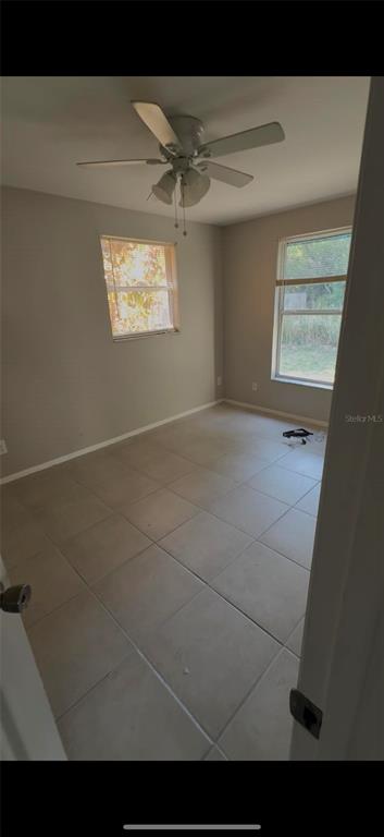 A bedroom with light-colored tile flooring, two windows, and a ceiling fan — 2121 33RD STREET, SARASOTA, FL