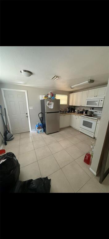 A kitchen with white cabinets, stainless steel appliances, and light-colored tile flooring — 2121 33RD STREET, SARASOTA, FL
