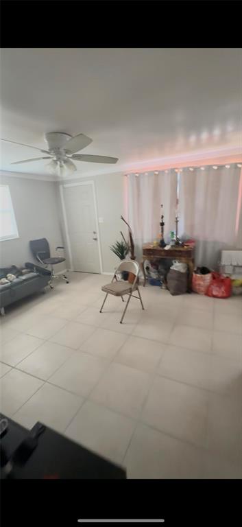 A room with light-colored tile flooring, a ceiling fan, a folding chair, and white curtains — 2121 33RD STREET, SARASOTA, FL