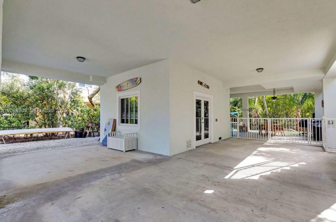 A covered concrete patio features a white exterior wall, a window, and a glass door — 1019 Snapper Ln, Key Largo FL 33037, KEY LARGO, FL
