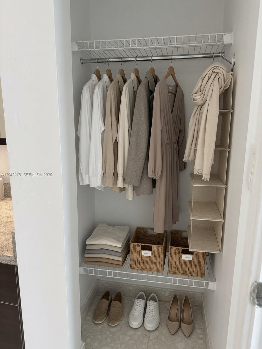 A reach-in closet features a wire shelf, hanging clothes, folded garments, baskets, and shoes — 185 SW 7th St # 3009, Miami FL 33130, MIAMI, FL