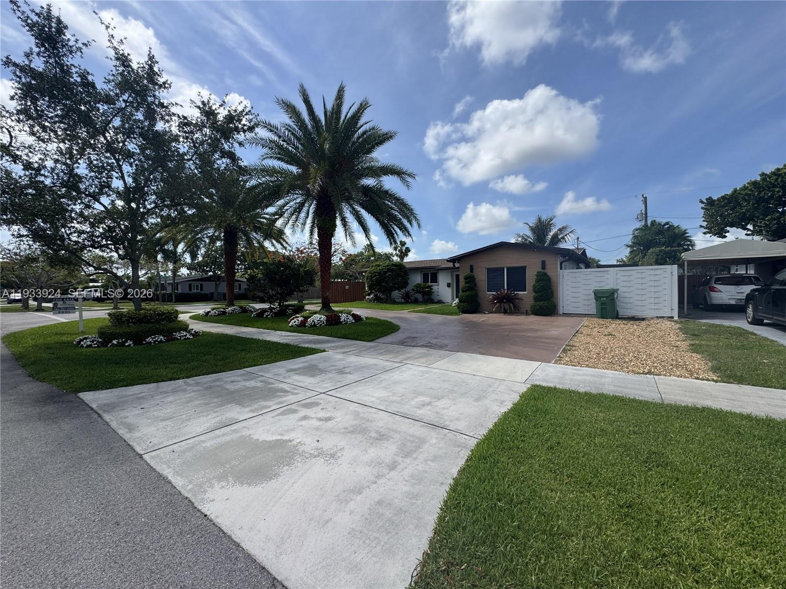 A single-story house features a concrete driveway, palm trees, and a white privacy fence — 9300 SW 192nd Dr, Cutler Bay FL 33157, CUTLER BAY, FL