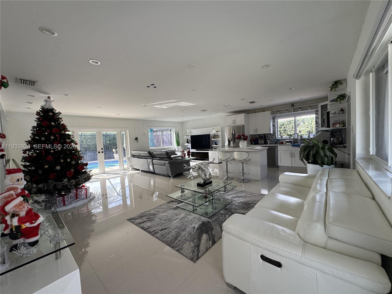 An open-concept living room and kitchen featuring white tile floors, a Christmas tree, and furniture — 9300 SW 192nd Dr, Cutler Bay FL 33157, CUTLER BAY, FL