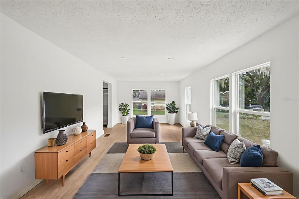 A living room features a gray sofa, armchair, wood coffee table, and a wall-mounted television — 1427 COMBEE LANE, LAKELAND, FL