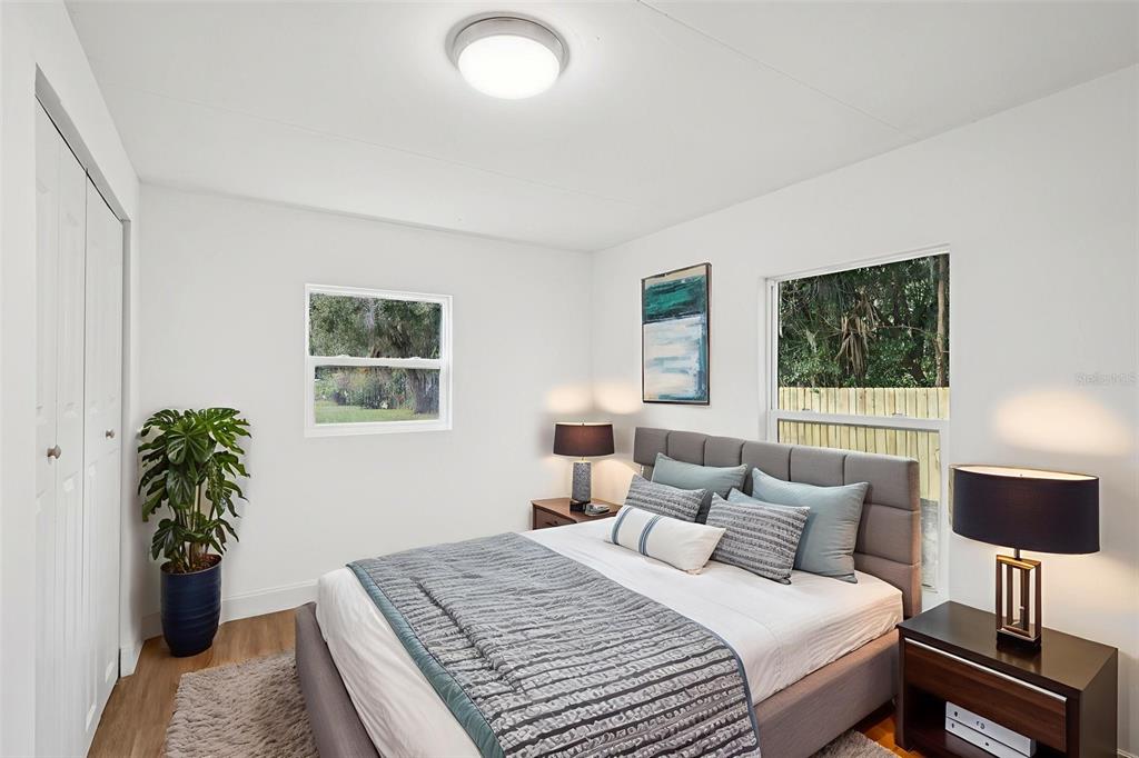 A bedroom features a gray upholstered bed, two nightstands with lamps, and a potted plant — 1427 COMBEE LANE, LAKELAND, FL