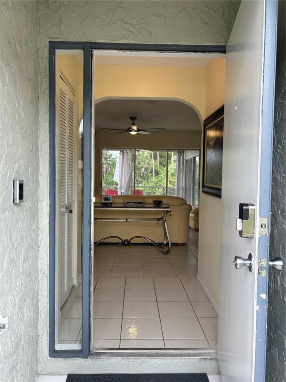 An open front door reveals a tiled entryway leading into a living room with a sofa — 2477 CANNOLOT BOULEVARD, PORT CHARLOTTE, FL