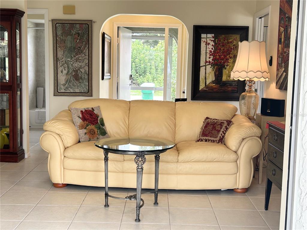 A living room features a cream leather sofa, a glass-topped table, and framed wall art — 2477 CANNOLOT BOULEVARD, PORT CHARLOTTE, FL