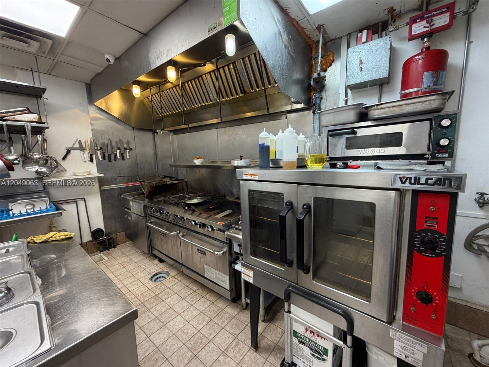 A commercial kitchen features stainless steel appliances, a range hood, and tiled flooring — Restaurant space NW For Lease, Miami FL 33122, MIAMI, FL