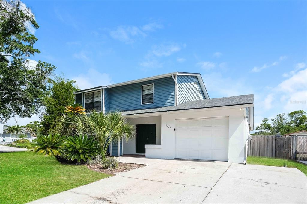 A two-story house with blue siding, a white garage, and a front yard with palms — 8229 MALVERN CIRCLE, TAMPA, FL