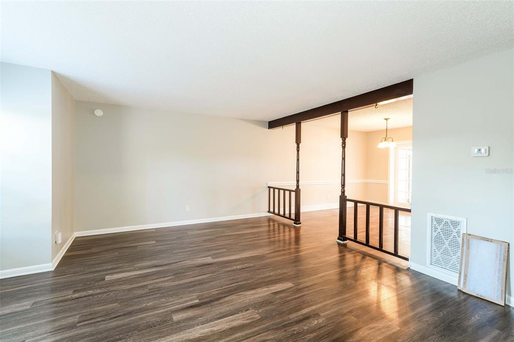 A living room with wood-look flooring, a popcorn ceiling, and a wooden room divider — 8229 MALVERN CIRCLE, TAMPA, FL