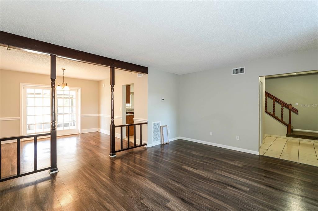 A living room with wood-look flooring, a wooden room divider, and a staircase in view — 8229 MALVERN CIRCLE, TAMPA, FL