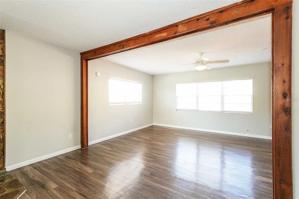 A living room with wood-look flooring, light walls, and a large wooden structural beam — 8229 MALVERN CIRCLE, TAMPA, FL