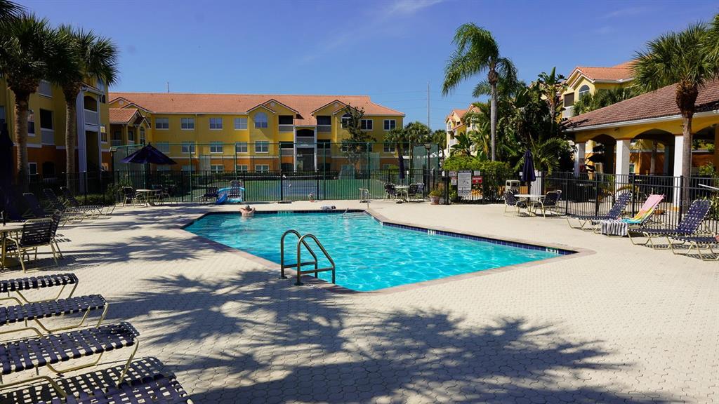 A swimming pool is surrounded by lounge chairs and palm trees in front of apartment buildings — 10764 70TH AVENUE UNIT 2208, SEMINOLE, FL