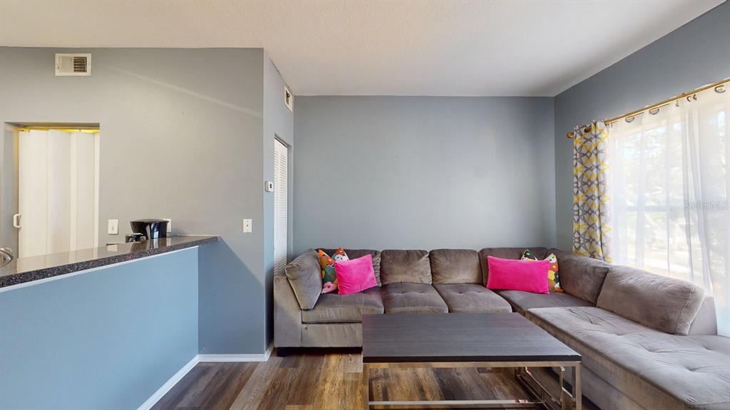 A living room features a grey sectional sofa, a coffee table, and blue walls — 10764 70TH AVENUE UNIT 2208, SEMINOLE, FL