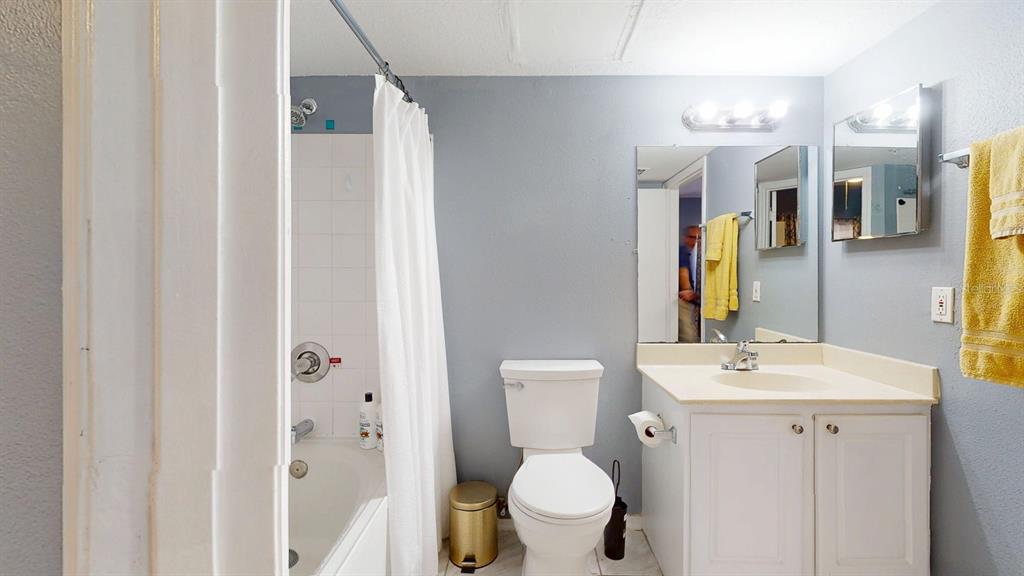 A bathroom features a white vanity, a toilet, and a shower-tub combination with a curtain — 10764 70TH AVENUE UNIT 2208, SEMINOLE, FL