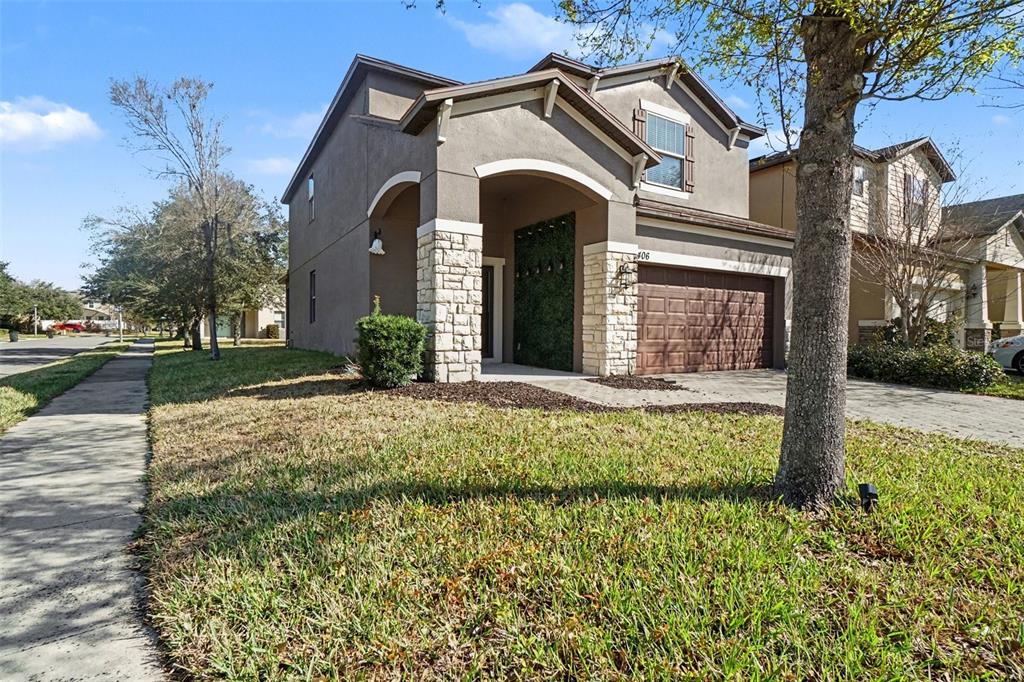 A two-story suburban house features a stone-accented entryway, a brown garage door, and stucco siding — 406 CAPRON ASH LOOP, CASSELBERRY, FL