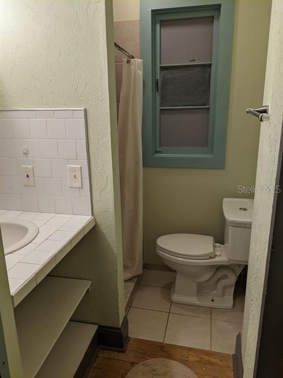 A bathroom features a tiled vanity, a white toilet, and a shower with a curtain — 401 COLONIA LANE E UNIT 13, NOKOMIS, FL