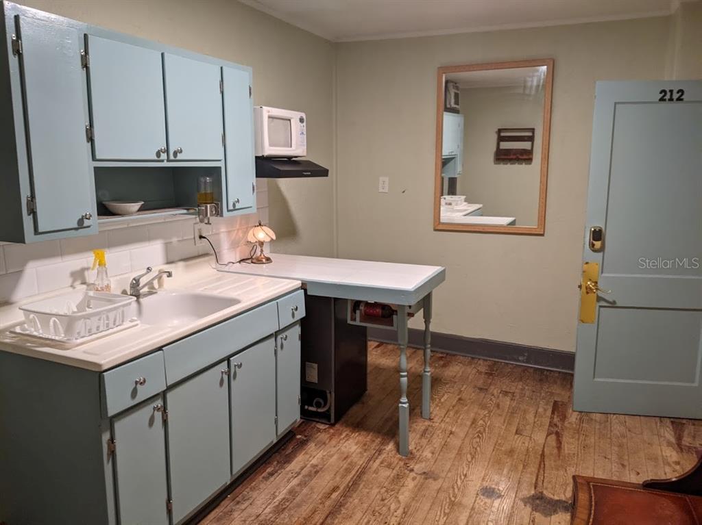 A kitchen with light blue cabinets, a white sink, and a wooden floor — 401 COLONIA LANE E UNIT 13, NOKOMIS, FL