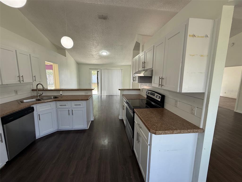 A kitchen with white cabinets, brown countertops, and dark wood-look flooring — 13102 LINDEN DRIVE, SPRING HILL, FL