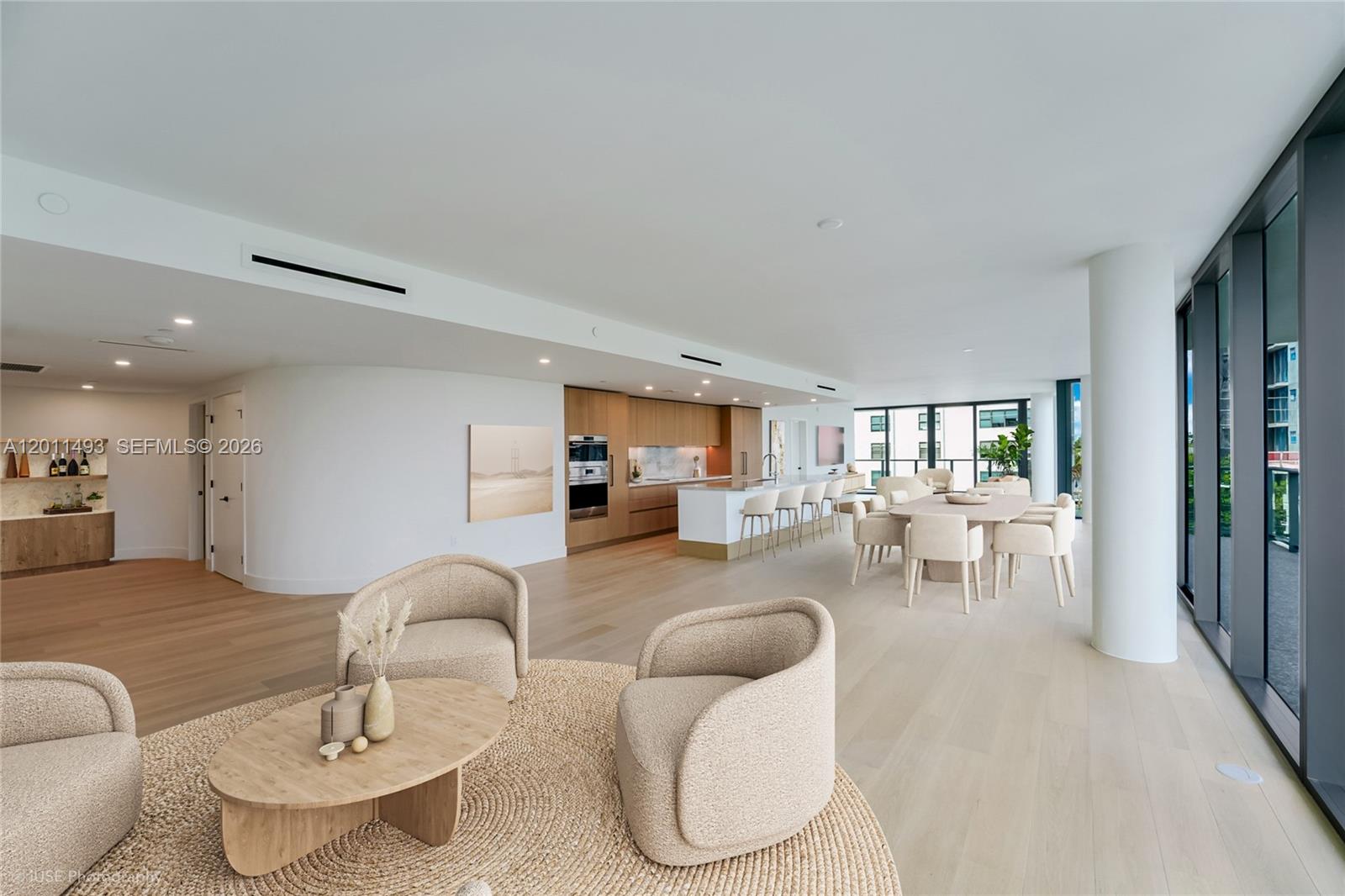 An open-concept living and dining area features light wood flooring, modern cabinetry, and floor-to-ceiling windows — 1177 Kane Concourse # 405, Bay Harbor Islands FL 33154, BAY HARBOR ISLANDS, FL