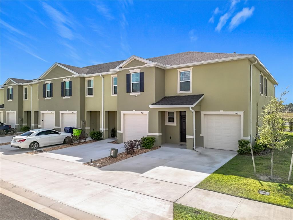 A row of attached two-story townhomes with light green stucco siding and concrete driveways — 965 LIDO DRIVE, HOWEY IN THE HILLS, FL